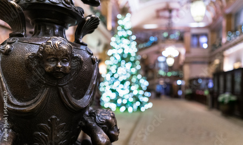 A closeup, landscape view of a a sculpture with a christmas tree in the background in a spacious hotel lobby