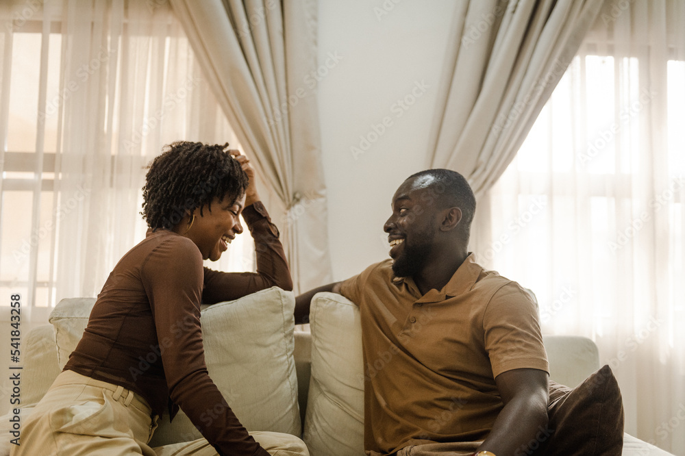black couple sitting on sofa and laughing together black couple sitting on sofa and laughing together