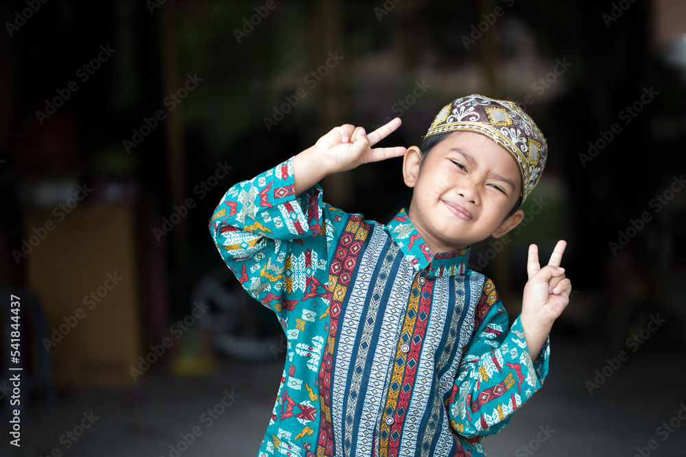 Asian Muslim boy making cute poses in Muslim clothes Asian Muslim boy making cute poses in Muslim clothes