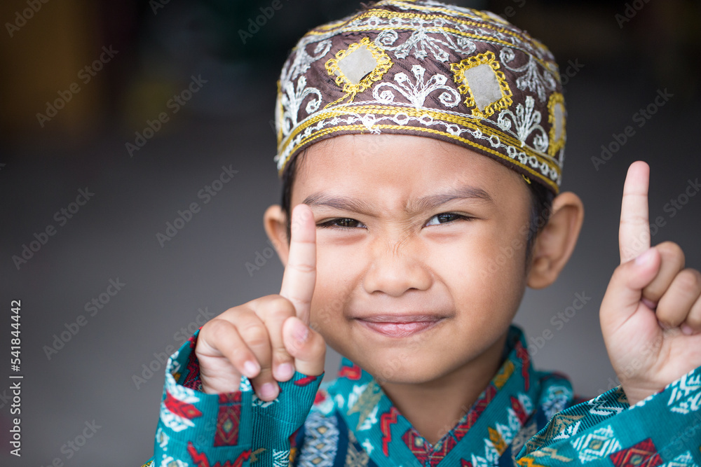 Asian Muslim boy making cute poses in Muslim clothes Asian Muslim boy making cute poses in Muslim clothes