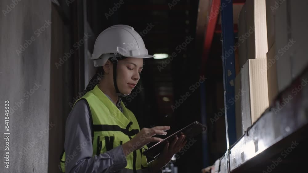 Woman manager operate in warehouses use radios walkie-talkies and tablet to inspect cartons on racks or shelves, Logistics, Import, Export, Shipping yard, Work at night. Woman manager operate in warehouses use radios walkie-talkies and tablet to inspect cartons on racks or shelves, Logistics, Import, Export, Shipping yard, Work at night.