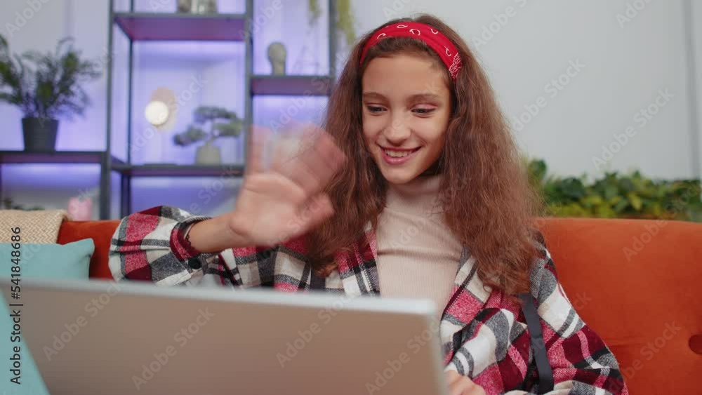 Portrait of preteen girl sitting on couch, looking at camera, making video webcam conference call with friends or family, enjoying pleasant conversation. Young child, kid laughing waving hello at home Portrait of preteen girl sitting on couch, looking at camera, making video webcam conference call with friends or family, enjoying pleasant conversation. Young child, kid laughing waving hello at home