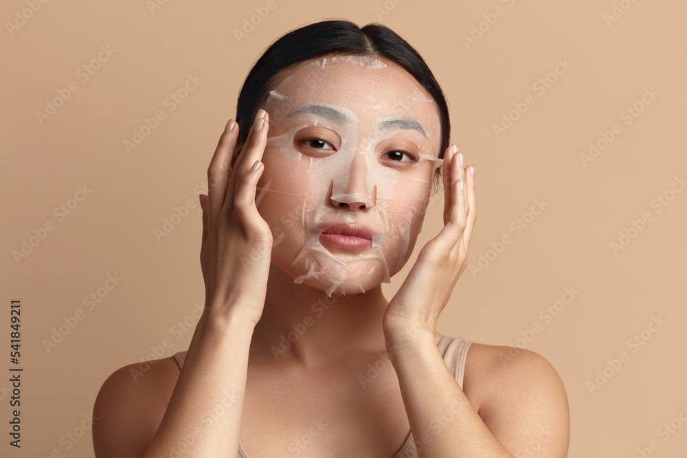 Beauty Woman Face Mask. Portrait Of Beautiful Girl Posing in Sheet Mask
