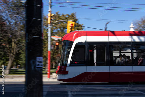 A modern streetcar, light rail, is seen on a downtown city street, urban area during a clear, blue sky day.