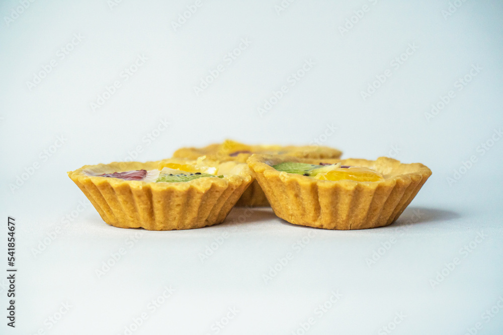A small plate of a typical Indonesian snack called Pie Susu topped with slices of orange, strawberry and kiwi, served on a white background A small plate of a typical Indonesian snack called Pie Susu topped with slices of orange, strawberry and kiwi, served on a white background
