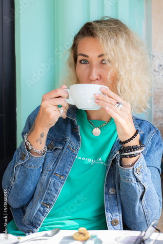 Beautiful blonde woman enjoying the cup of cappuccino in the morning at cafe. photo