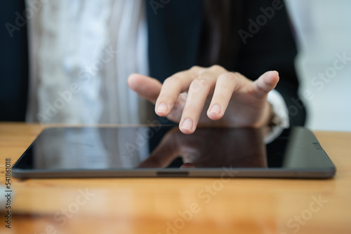 Close-up photo of a businesswoman s hand using a digital tablet in the office.