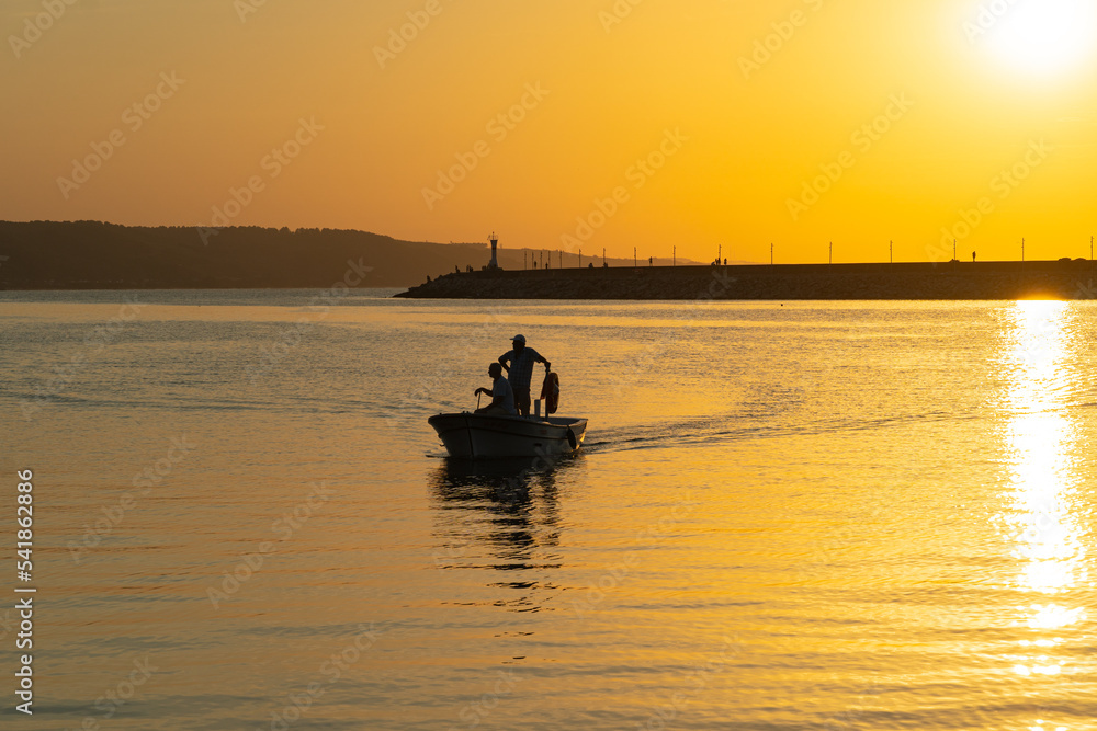 Silhouettes of two fishermen in a boat in the harbor at sunset, Turkey photo