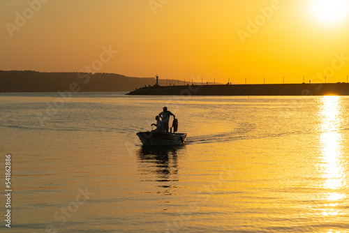 Silhouettes of two fishermen in a boat in the harbor at sunset, Turkey photo