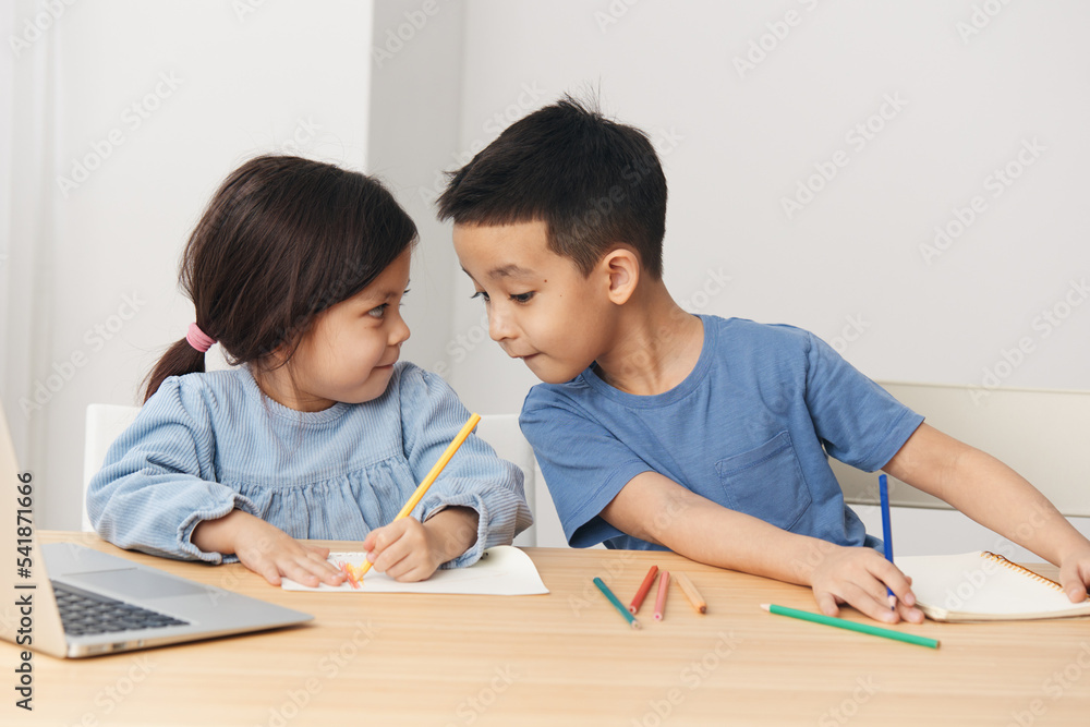 children draw with colored pencils sitting at the table and talking to each other children draw with colored pencils sitting at the table and talking to each other