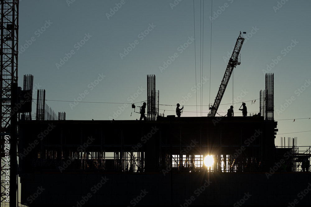 Builder workers working on construction site and sunset, beam, steel structure. Workers build large buildings on the construction site. Workers silhouette on construction safety working.blur
