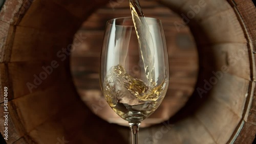 Super Slow Motion Shot of Pouring White Wine into Glass inside Wooden Barrel at 1000fps. photo