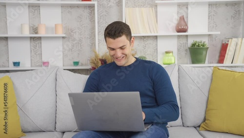 Happy man enjoys working with laptop at home.
Man working pleasantly with laptop at home.
