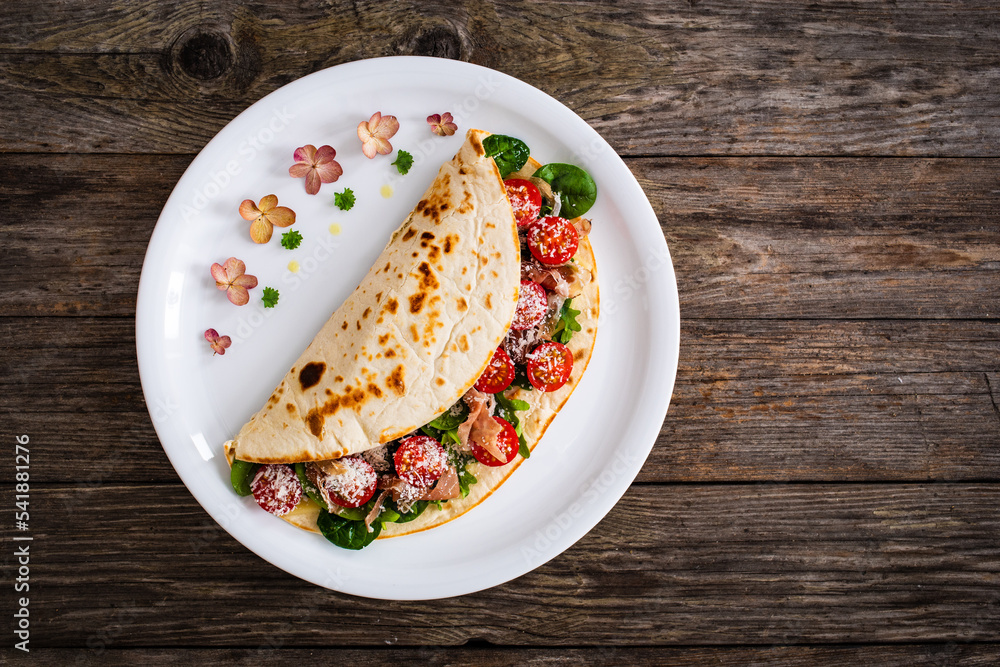 Italian piada wraps piadina stuffed with fresh vegetable leaves, parmesan and prosciutto crudo