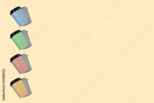 Four multi-colored cardboard coffee cups with a plastic lid on a beige background. Template with copy space. The concept of ecology, recycling, environmental protection
