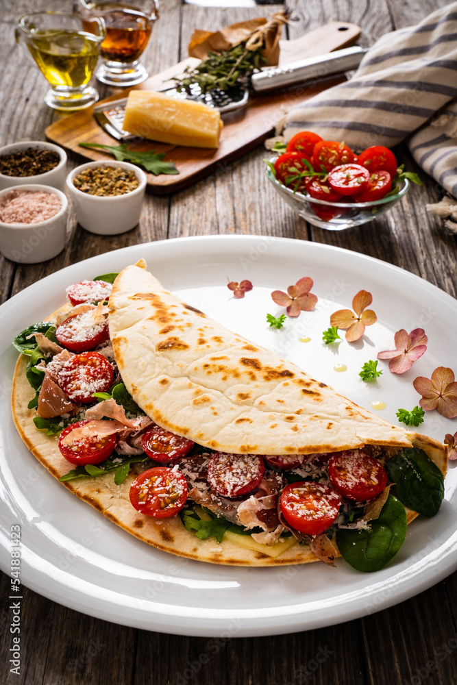Italian piada wraps piadina stuffed with fresh vegetable leaves, parmesan and prosciutto crudo
