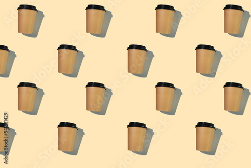 Pattern of cardboard coffee cups with a plastic lid with a hard shadow on a beige background. The concept of ecology, recycling, environmental protection