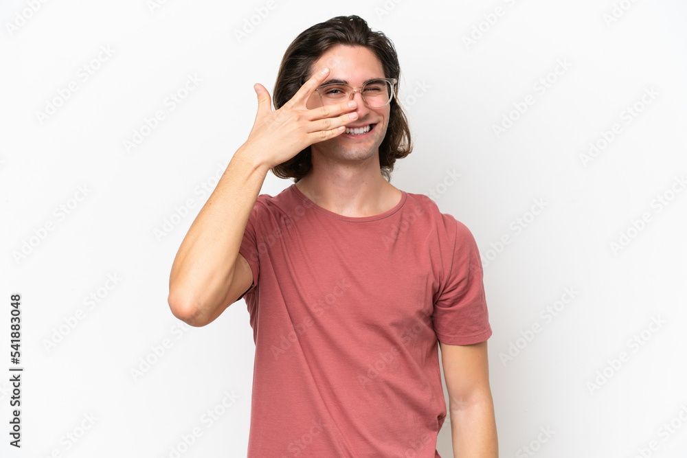 Young handsome man isolated on white background covering eyes by hands and smiling Young handsome man isolated on white background covering eyes by hands and smiling
