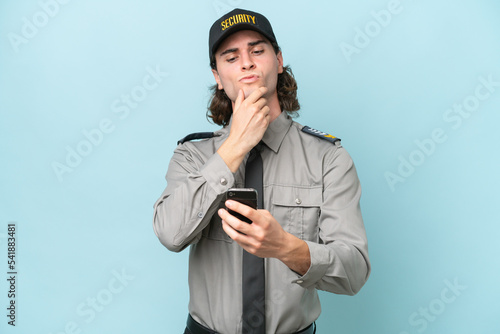 Young safeguard man isolated on blue background thinking and sending a message