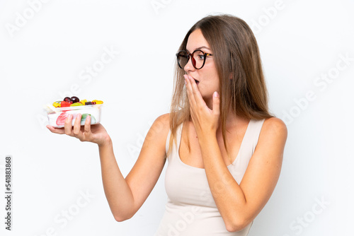 Young pretty woman holding a bowl of fruit isolated on white background with surprise and shocked facial expression