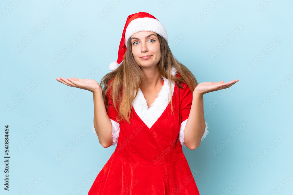 Young caucasian woman dressed as mama noel isolated on blue background having doubts while raising hands Young caucasian woman dressed as mama noel isolated on blue background having doubts while raising hands