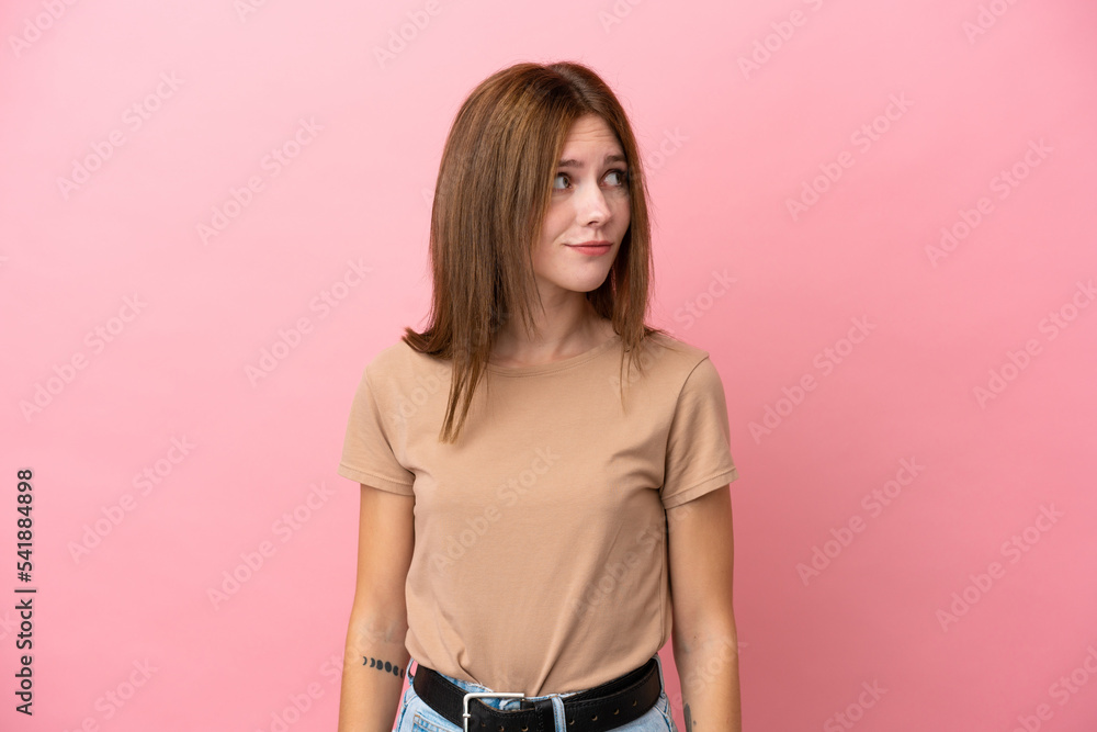 Young English woman isolated on pink background making doubts gesture looking side Young English woman isolated on pink background making doubts gesture looking side