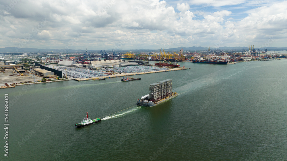 tugboat pulling ship equipment constrution in sea and commercial dock background,