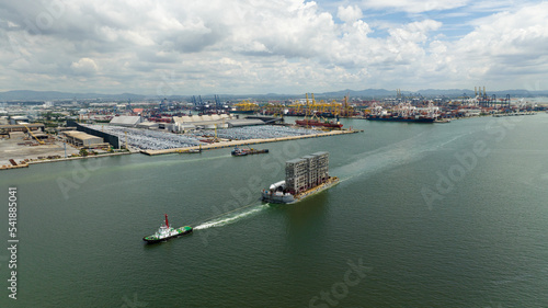 tugboat pulling ship equipment constrution in sea and commercial dock background,
