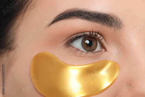 Fototapeta Young woman with golden under eye patch, closeup