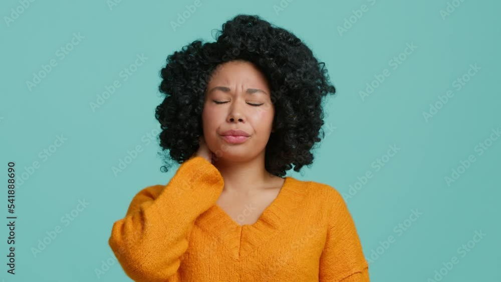 Close up suffering face of African American woman experiences severe pain in neck, rubbing it to relieve muscle tension. Cervical osteochondrosis, tired overworked female, sedentary lifestyle concept Close up suffering face of African American woman experiences severe pain in neck, rubbing it to relieve muscle tension. Cervical osteochondrosis, tired overworked female, sedentary lifestyle concept
