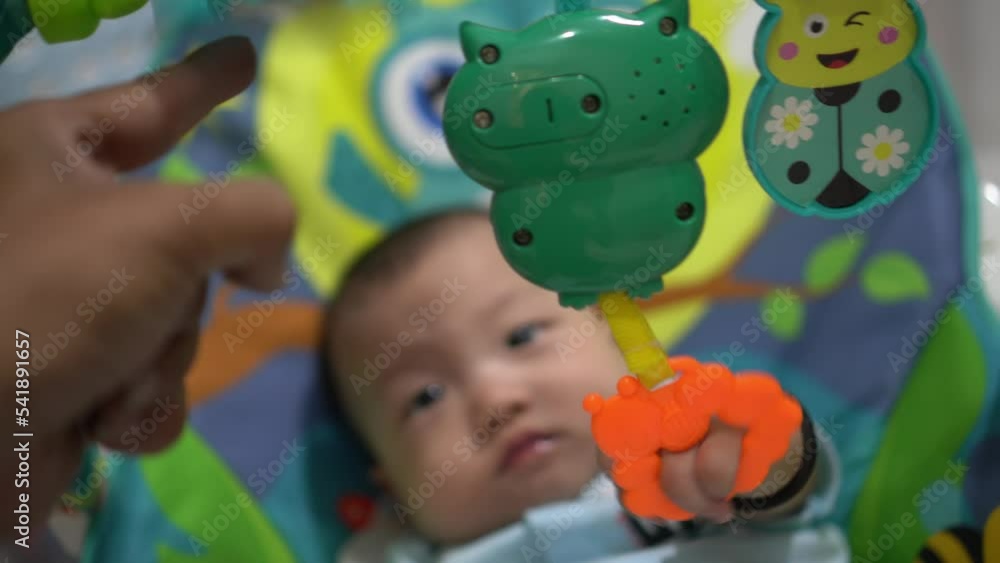 Selective focus baby hand pull the rattle musical rib toy. Father hand ...