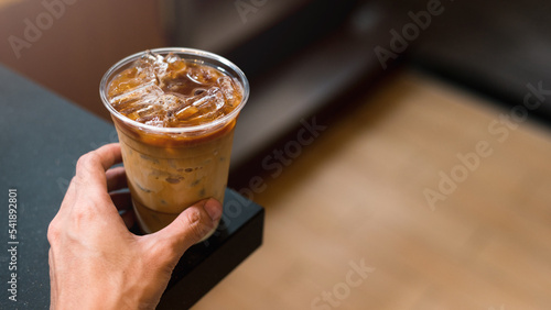 hand holding a take-out iced coffee on black table