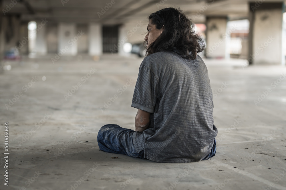 Fototapeta premium Homeless people sit on the streets in the shadows of buildings and ask for help and money the troubles of the big modern city.