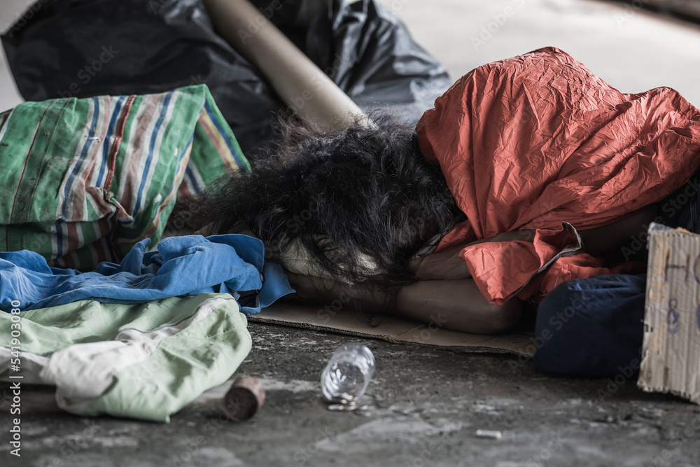 A homeless man sleeps on the street in the shadow of a building. and ask for help and money the troubles of the big modern city. A homeless man sleeps on the street in the shadow of a building. and ask for help and money the troubles of the big modern city.