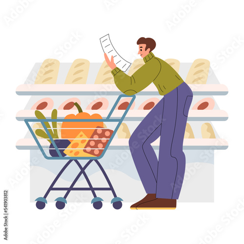 Man with shopping cart reading the shopping list in front of shelves with goods in supermarket