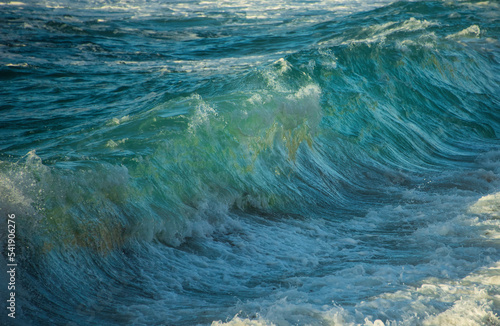 Large Powerful jade turquoise colored waves crashing at Sennen Cove in Cornwall during late sunset