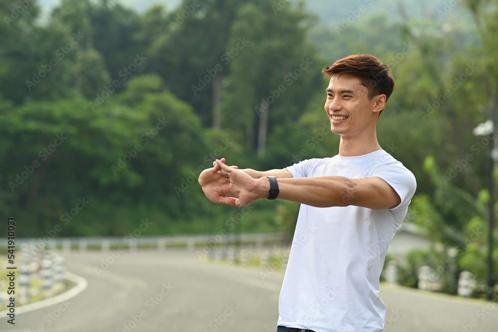 Happy handsome man stretching after workout session at the park in early morning. Fitness, sport and healthy lifestyle concept Happy handsome man stretching after workout session at the park in early morning. Fitness, sport and healthy lifestyle concept