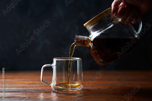 Tea poured from a teapot into a cup photo