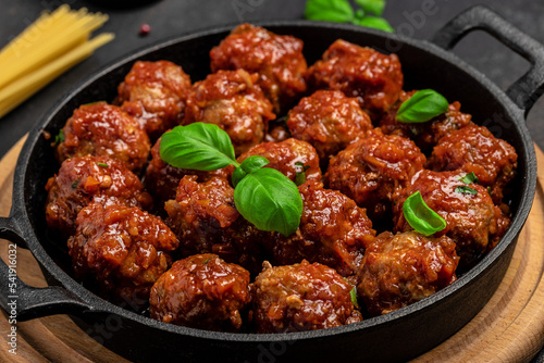 Meatballs in sweet and sour tomato sauce. in frying pan on dark background