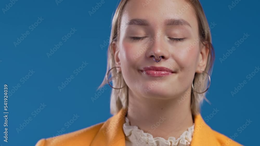 Friendly girl showing yes signal, nods head, approve. Positive smiling businees woman, body language. Blue background. Friendly girl showing yes signal, nods head, approve. Positive smiling businees woman, body language. Blue background.