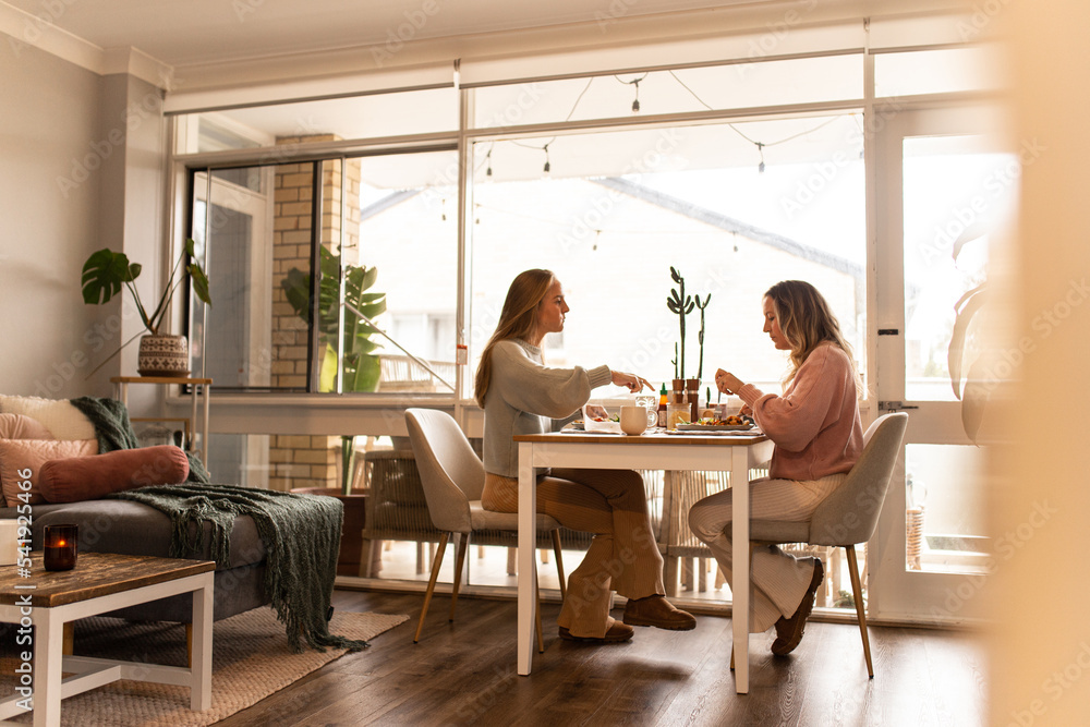 Female same sex couple eating a meal together at home Female same sex couple eating a meal together at home