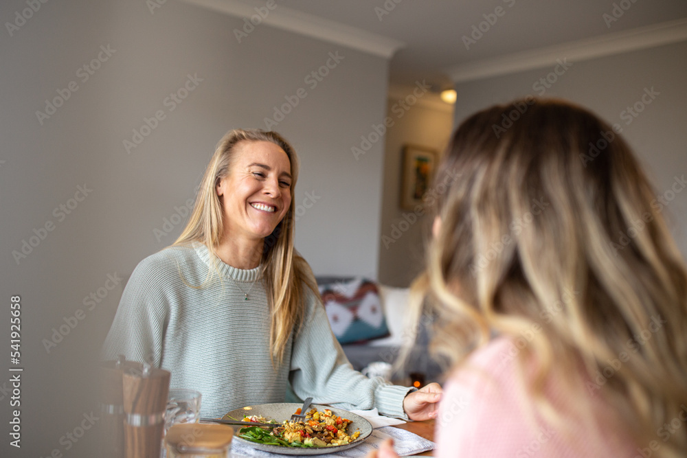 Same sex couple laughing and talking together at the dinner table Same sex couple laughing and talking together at the dinner table