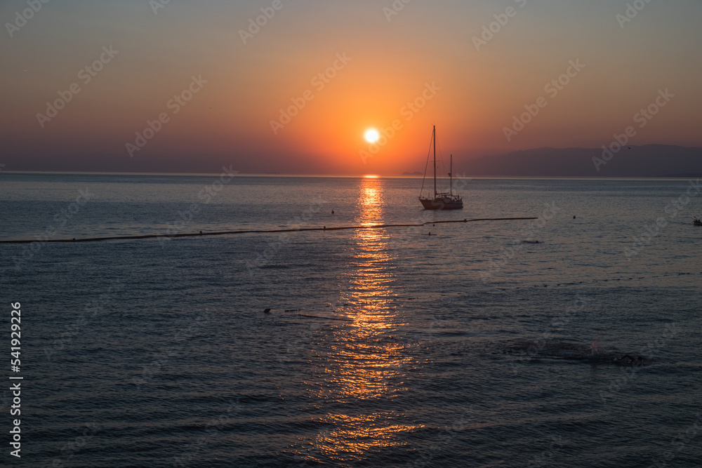 Sunset behind a sailboat in the Mediterranean sea, Camogli, Italy.