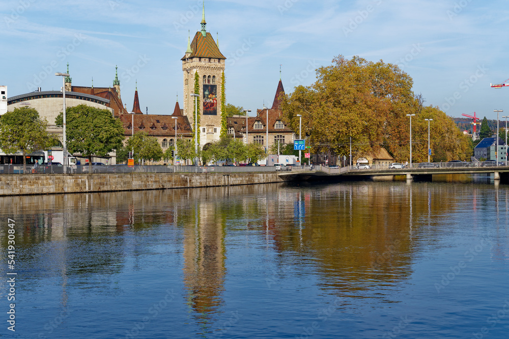 Stone tower of Swiss National Museum at City of Zürich with Limmat River in the foreground on a sunny autumn day. Photo taken October 29th, 2022, Zurich, Switzerland.