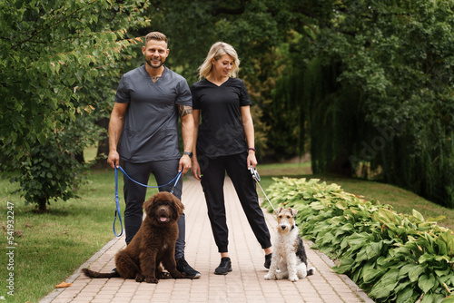 Portrait of glad couple walking in park with dogs on their holidays. © Fxquadro