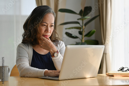 Old woman work at home using notebook computer.