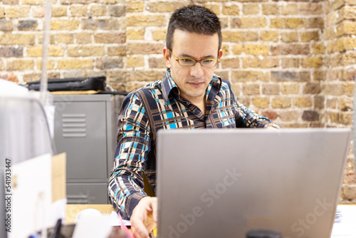 The Media Agency: Working Hard. Candid view of a creative professional concentrating on his work at his office desk. From a series of related images. photo