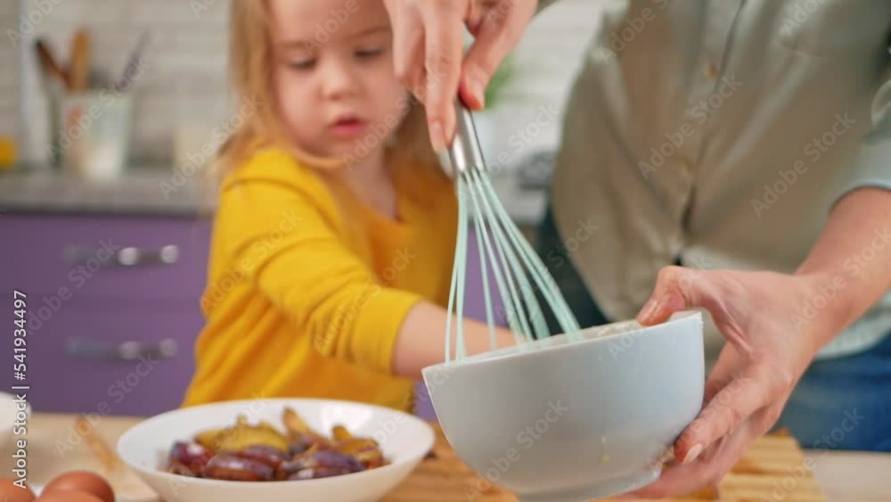 Grandmother and granddaughter cook in kitchen in middle, family pastime, leisure. woman and child make cake in purple, lavender kitchen. bowl and corolla Grandmother and granddaughter cook in kitchen in middle, family pastime, leisure. woman and child make cake in purple, lavender kitchen. bowl and corolla