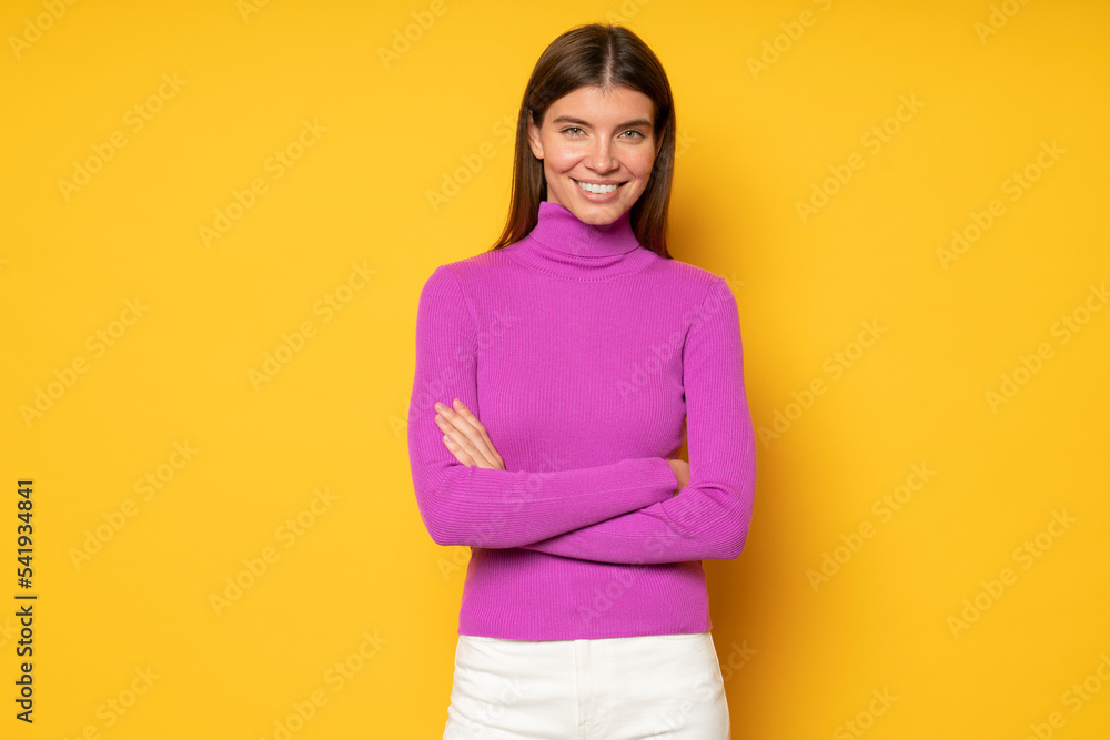 Bossy woman sharing secrets of successful start up standing on yellow background with crossed hands Bossy woman sharing secrets of successful start up standing on yellow background with crossed hands