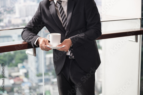 Unknown businessman holding coffee cup with city background 